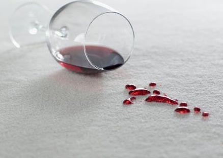 A glass of wine spills on the carpet